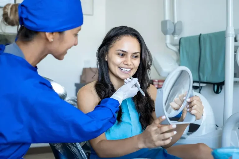 patient-smiles-looks-into-mirror-while-being-seen-by-dentist